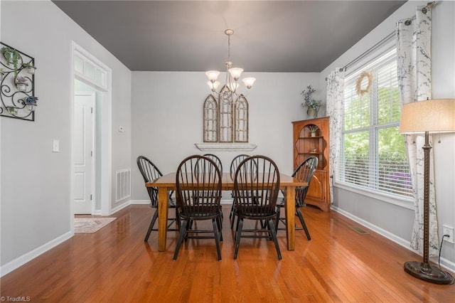 dining space featuring a chandelier, wood finished floors, and baseboards