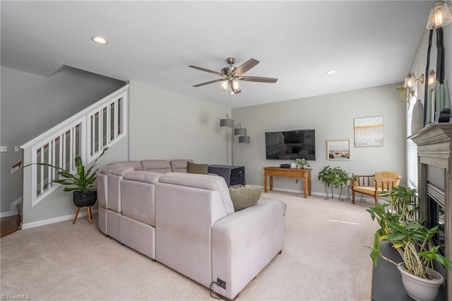carpeted living area featuring stairs, a ceiling fan, a fireplace, baseboards, and recessed lighting