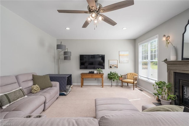 living area featuring light carpet, baseboards, a ceiling fan, a glass covered fireplace, and recessed lighting