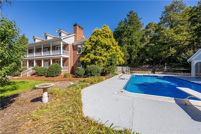 view of swimming pool with a patio and a diving board