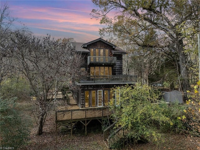 back house at dusk featuring a balcony