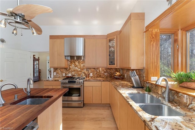 kitchen with butcher block countertops, light wood-type flooring, sink, and stainless steel stove