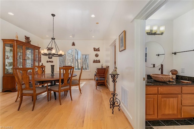 dining area with a notable chandelier, light wood-type flooring, and sink