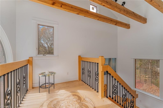 interior space with beamed ceiling, a towering ceiling, and light hardwood / wood-style flooring