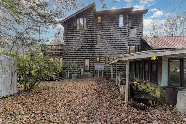 back of property with central AC unit and a sunroom