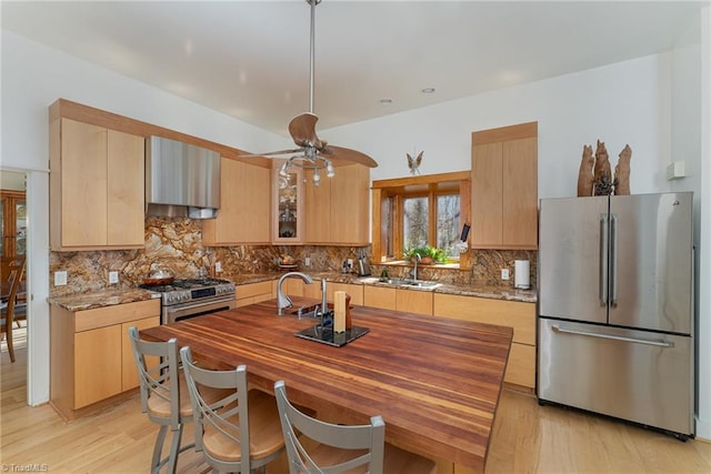 kitchen with sink, light stone counters, light hardwood / wood-style floors, light brown cabinetry, and appliances with stainless steel finishes