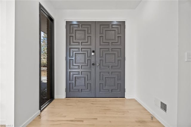 foyer featuring visible vents, light wood-style flooring, and baseboards