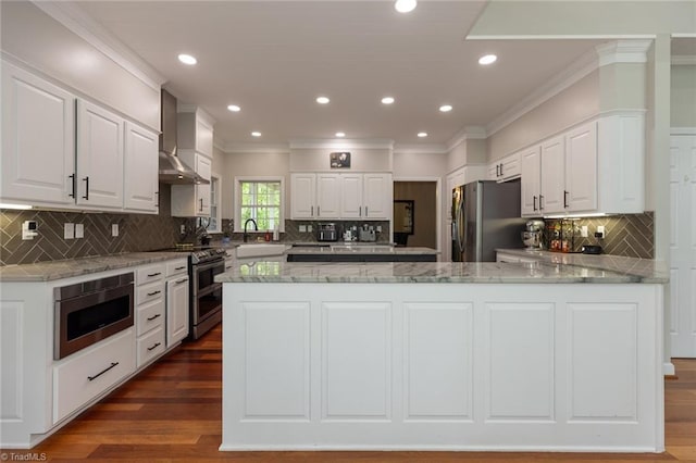 kitchen featuring crown molding, decorative backsplash, appliances with stainless steel finishes, and wall chimney exhaust hood