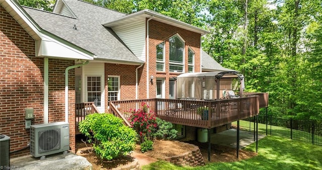back of house with brick siding, fence, ac unit, a shingled roof, and a wooden deck