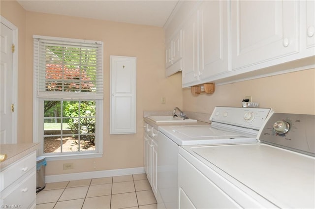 laundry area featuring independent washer and dryer, baseboards, light tile patterned floors, a sink, and cabinet space