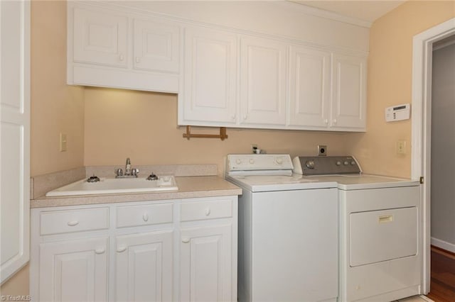 clothes washing area with cabinet space, independent washer and dryer, and a sink