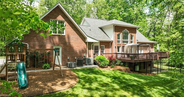 back of house with brick siding, a yard, a wooden deck, ac unit, and a playground