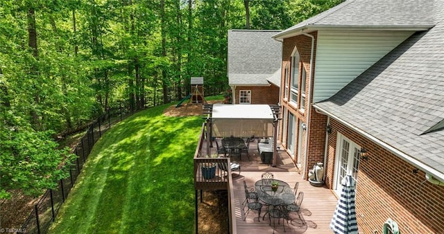 view of yard with a playground, a fenced backyard, a wooden deck, and outdoor dining space