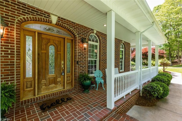 entrance to property with brick siding and a porch