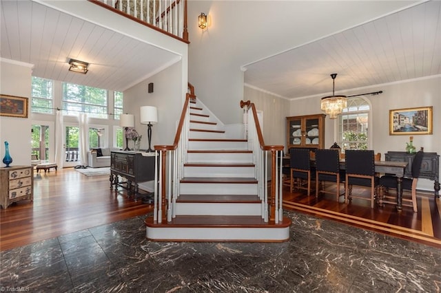 stairs featuring crown molding, a chandelier, and a healthy amount of sunlight