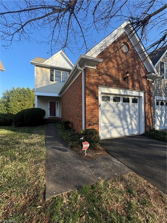 traditional home with aphalt driveway, a garage, and brick siding