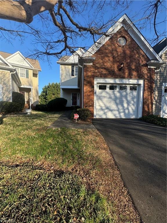 view of front of property with a garage, a front yard, brick siding, and driveway