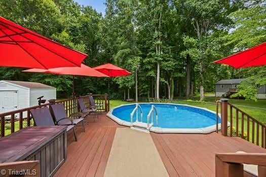 1630 Ploughboy Ln, Winston-Salem, NC 27103 - outdoor pool with a shed, a deck, view of scattered trees, and a lawn