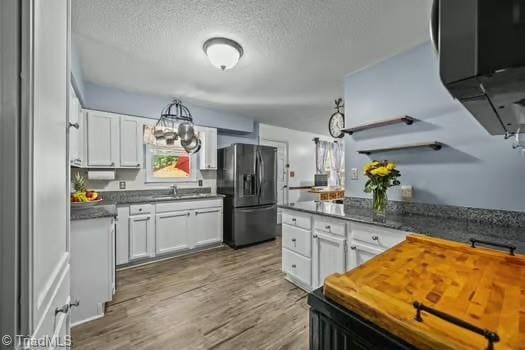 1630 Ploughboy Ln, Winston-Salem, NC 27103 - kitchen with black fridge with ice dispenser, white cabinetry, a textured ceiling, wood finished floors, and butcher block counters