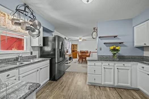 1630 Ploughboy Ln, Winston-Salem, NC 27103 - kitchen with freestanding refrigerator, white cabinetry, light wood-style flooring, and dark stone counters