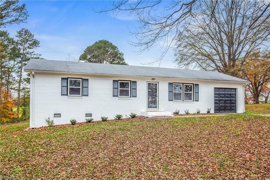 single story home with a garage, a front yard, crawl space, and brick siding