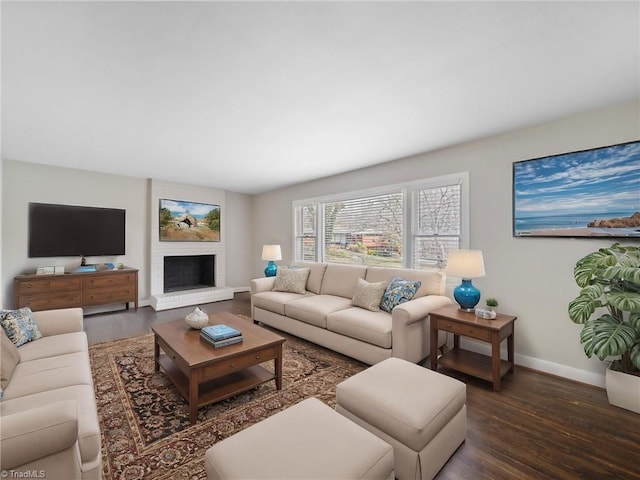 living room featuring a brick fireplace, baseboards, and wood finished floors