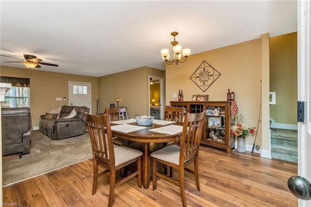 dining room with ceiling fan with notable chandelier and light hardwood / wood-style flooring