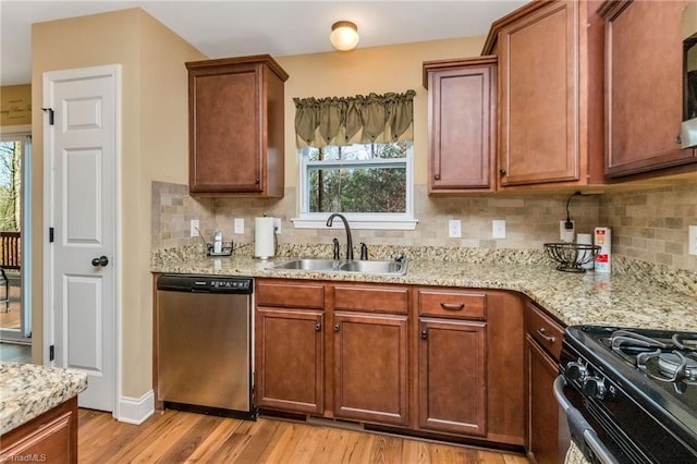 kitchen with sink, stainless steel dishwasher, plenty of natural light, light hardwood / wood-style floors, and light stone counters