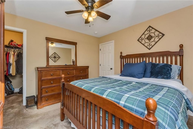 carpeted bedroom featuring a walk in closet, a closet, and ceiling fan