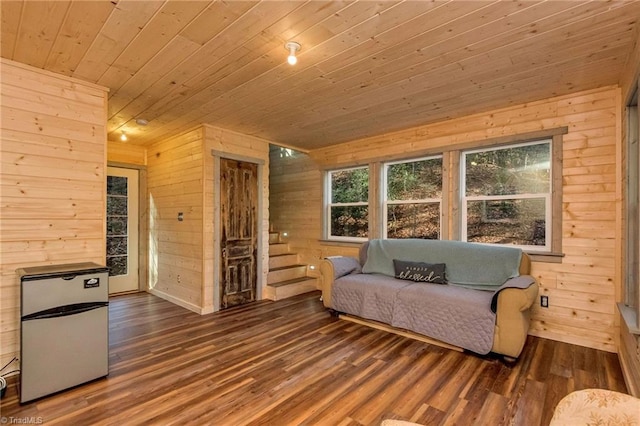 living area with dark hardwood / wood-style floors, wood ceiling, and wooden walls