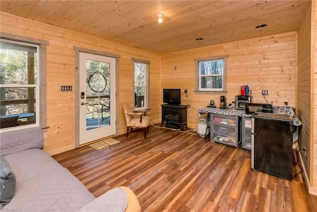 living room featuring wood walls, wooden ceiling, dark wood-type flooring, and a wood stove