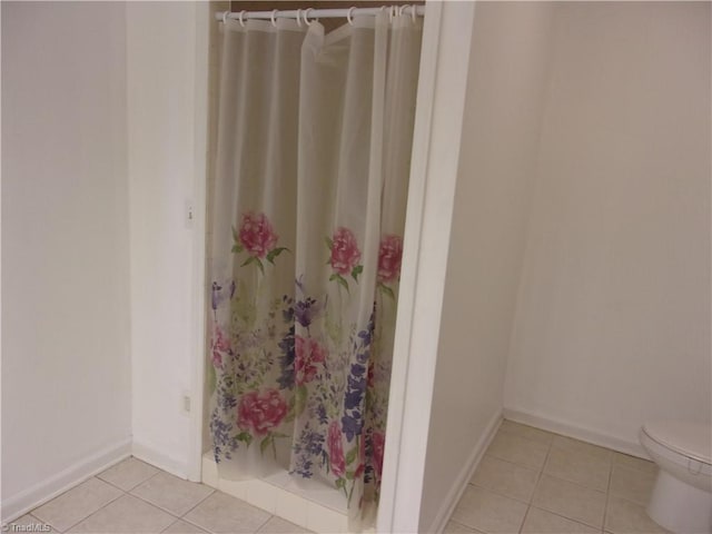 bathroom featuring curtained shower, toilet, and tile patterned floors