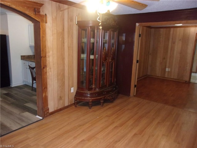 interior space with light hardwood / wood-style flooring, wooden walls, and ceiling fan