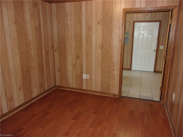 unfurnished room featuring wooden walls and hardwood / wood-style flooring