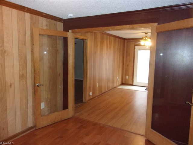 empty room with ceiling fan, hardwood / wood-style flooring, and wooden walls