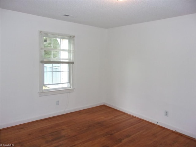 unfurnished room featuring wood-type flooring and a textured ceiling