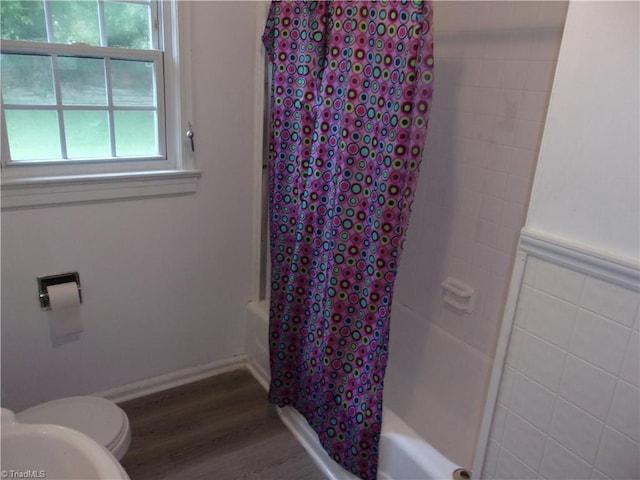 bathroom with wood-type flooring, shower / bath combo, and toilet