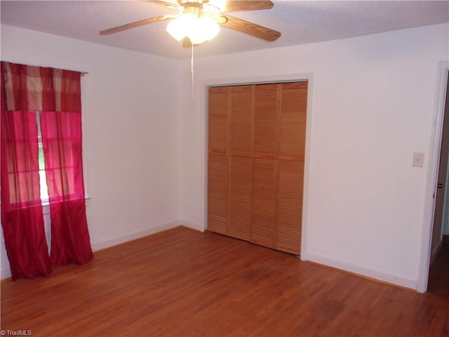 unfurnished bedroom with ceiling fan, a closet, and wood-type flooring