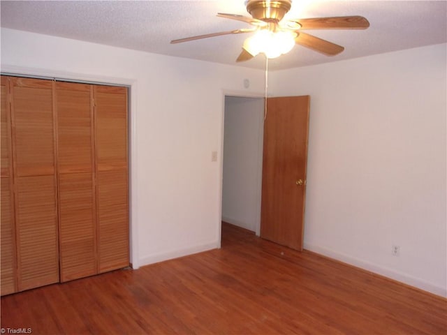 unfurnished bedroom with ceiling fan, hardwood / wood-style flooring, and a closet