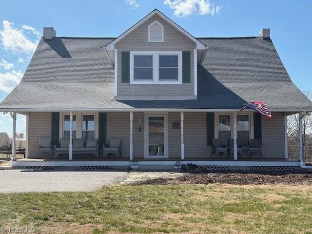 farmhouse inspired home with a porch, a chimney, and a front lawn