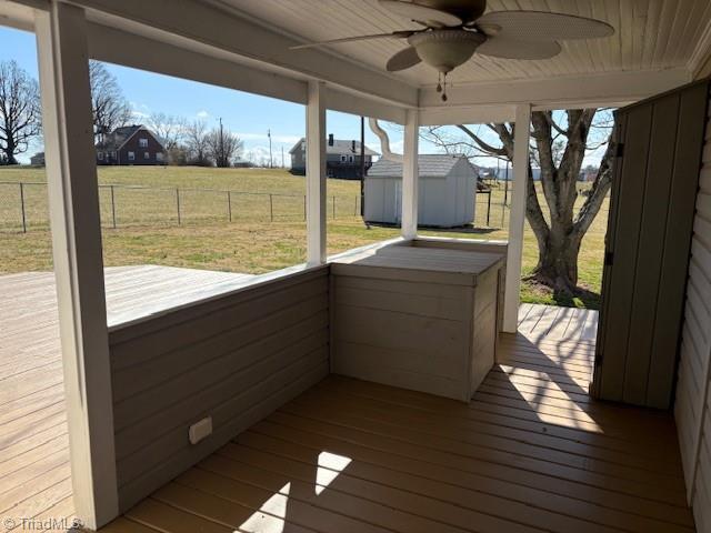 wooden deck with ceiling fan, an outbuilding, fence, a storage unit, and a yard