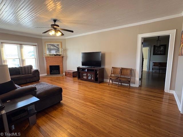 living area featuring crown molding, baseboards, and wood finished floors