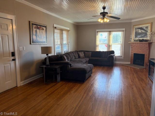 living room featuring baseboards, ceiling fan, hardwood / wood-style floors, crown molding, and a brick fireplace