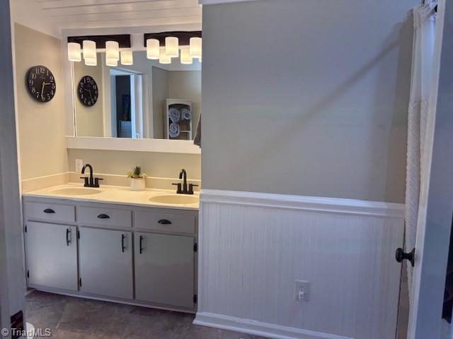 full bathroom with wainscoting, a sink, and double vanity