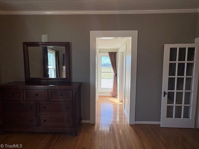 hallway featuring light wood-type flooring, baseboards, and crown molding