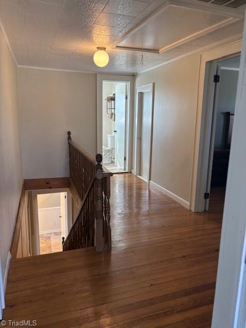 corridor featuring attic access, baseboards, an upstairs landing, and hardwood / wood-style flooring