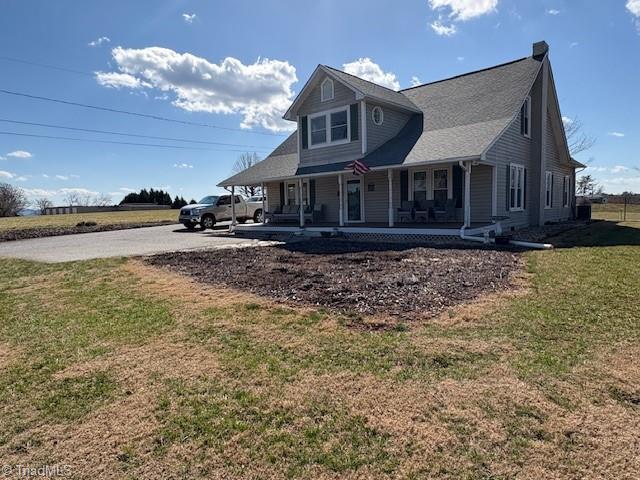 exterior space with driveway, covered porch, and a yard