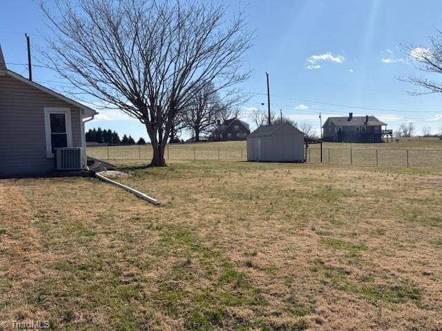 view of yard featuring central air condition unit, fence, an outdoor structure, and a shed