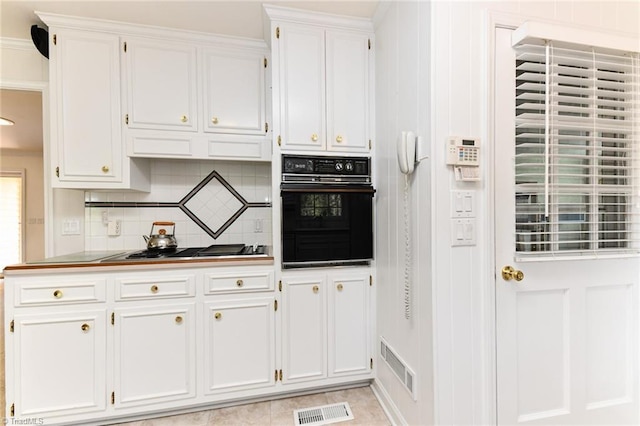 kitchen with white cabinets, black oven, stainless steel cooktop, and visible vents