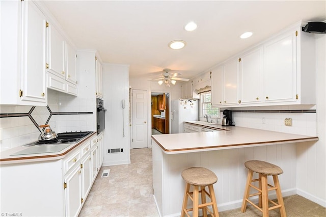 kitchen with white cabinetry, oven, white refrigerator with ice dispenser, visible vents, and a peninsula